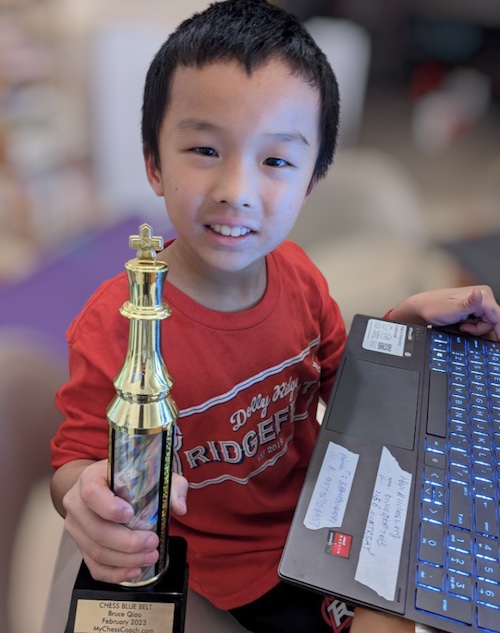 Bruce, Age 8, MyChessCoach student holding a chess tournament trophy