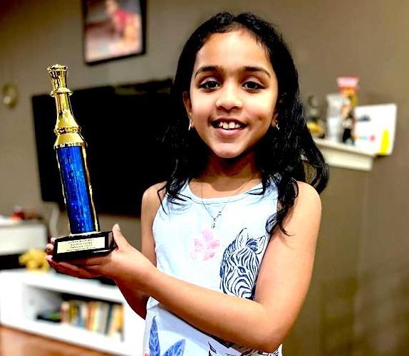 Anaya, Age 7, MyChessCoach student holding a chess tournament trophy