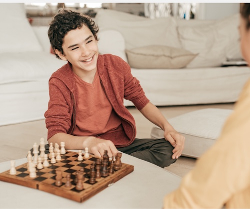 A Coach giving a 1:1 chess lesson to a young Student